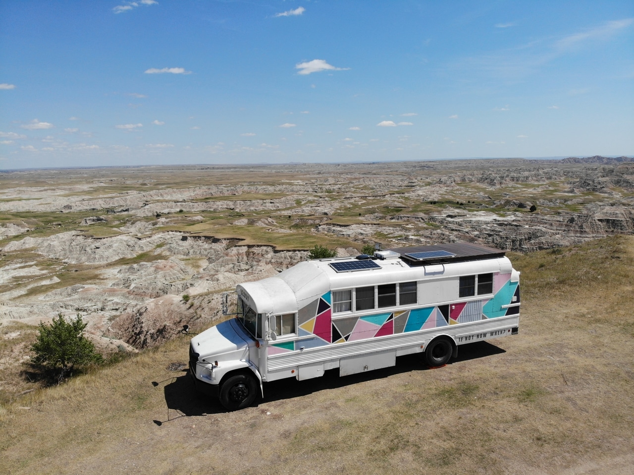 Aerial drone view of a colorful converted school bus parked in the Badlands