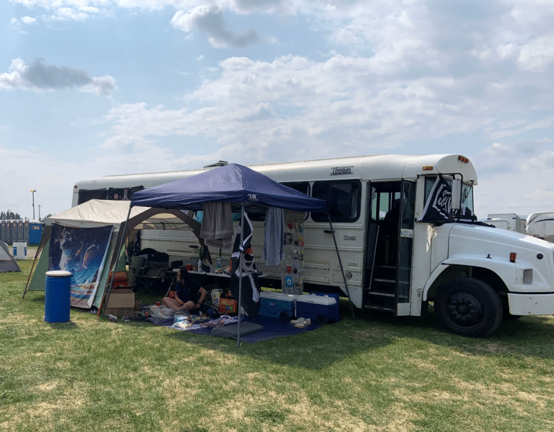 Converted school bus parked at a campground with awning extended