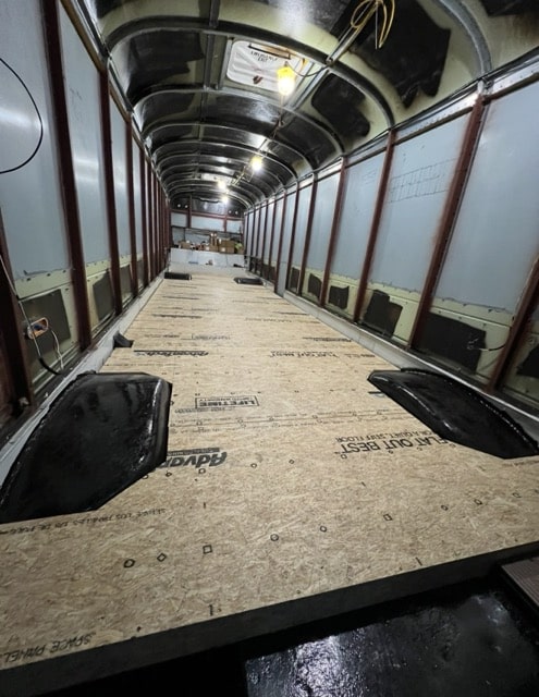 Inside of a school bus with all seats removed and subfloor installed