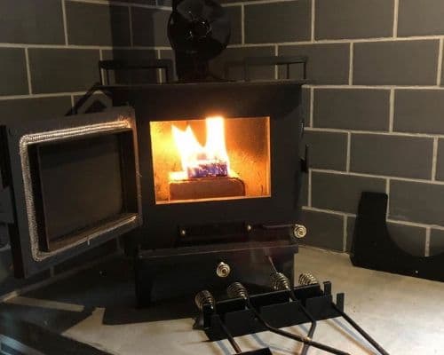 Cubic Mini wood stove burning inside a converted school bus with tile backsplash